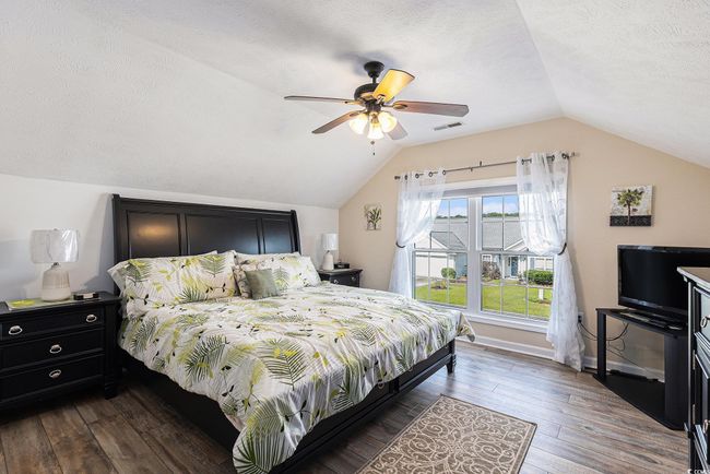 Bedroom featuring lofted ceiling, dark wood-style floors, ceiling fan, a textured ceiling, and baseboards | Image 29