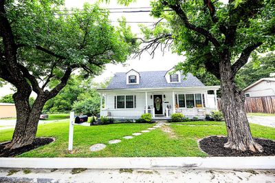 Cape cod-style house featuring a front yard and covered porch | Image 1