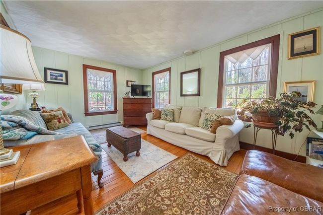 Living room featuring a decorative wall, baseboard heating, and hardwood / wood-style flooring | Image 7