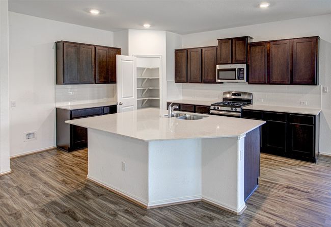 Kitchen featuring stainless steel appliances, a sink, backsplash, wood finished floors, and recessed lighting | Image 9