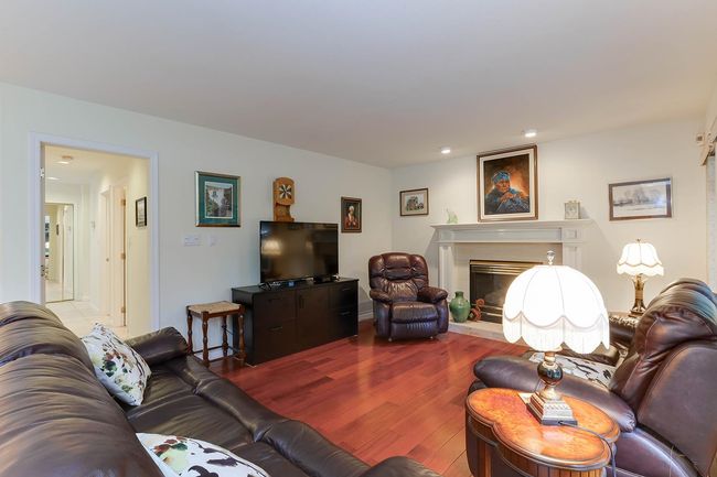 Living room featuring a fireplace with raised hearth and wood finished floors | Image 18