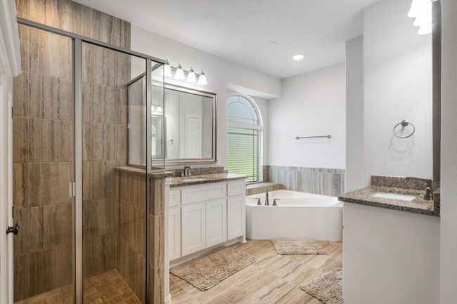 Bathroom with two vanities, a garden tub, a shower stall, and wood finished floors | Image 22