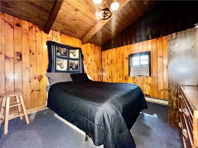 Bedroom with lofted ceiling with beams, wood ceiling, carpet, wood walls, and a baseboard heating unit | Image 7