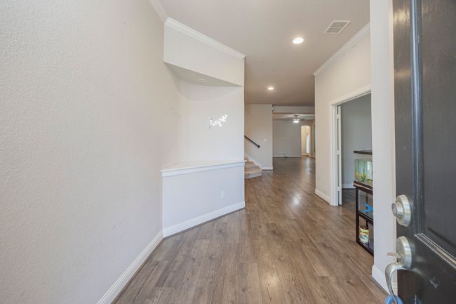 Hall with ornamental molding, stairway, wood finished floors, and recessed lighting | Image 6