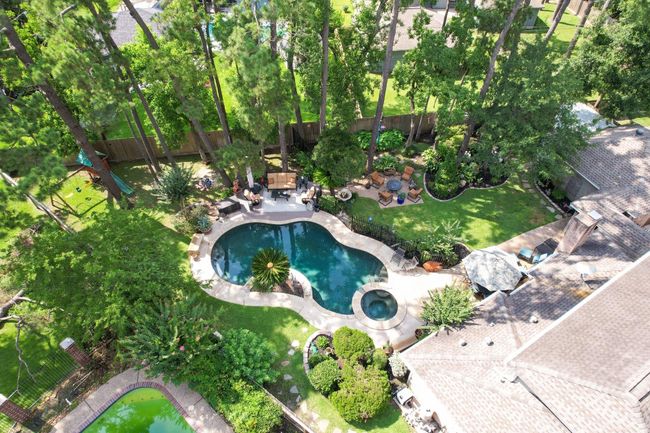 This aerial view showcases a private backyard paradise on an oversized wooded lot, featuring a beautifully designed free-form pool and spa, multiple outdoor entertaining areas, mature tree canopy, and attractively landscaped grounds that create the ultimate retreat for relaxation and recreation. | Image 30