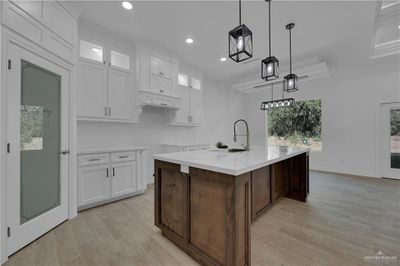 Kitchen with white cabinets, a center island with sink, and light hardwood / wood-style flooring | Image 3