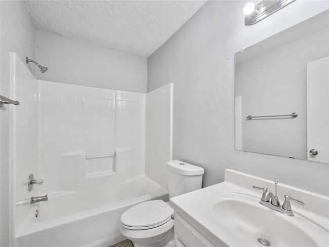 Full bathroom with a textured ceiling, toilet, shower / bath combination, and vanity | Image 5