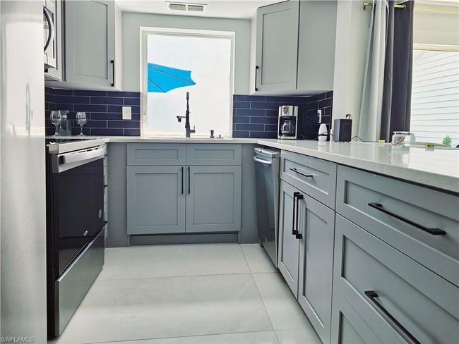 Kitchen featuring stainless steel appliances, a sink, and gray cabinets | Image 17