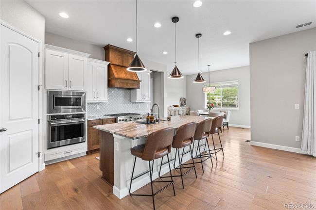 Chef's dream kitchen with upgraded pendant lighting, GE Cafe appliances (6-burner gas range, wall oven/airfryer, French door refrigerator) custom range hood and herringbone tile backsplash. Large granite island soft-close maple cabinets will roll-out drawers and large pantry. | Image 16
