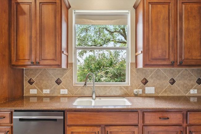 Kitchen featuring stainless steel dishwasher, brown cabinets, and decorative backsplash | Image 15