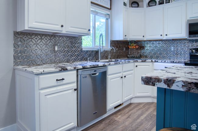Kitchen featuring white cabinets, wood finished floors, stainless steel dishwasher, and light stone counters | Image 8