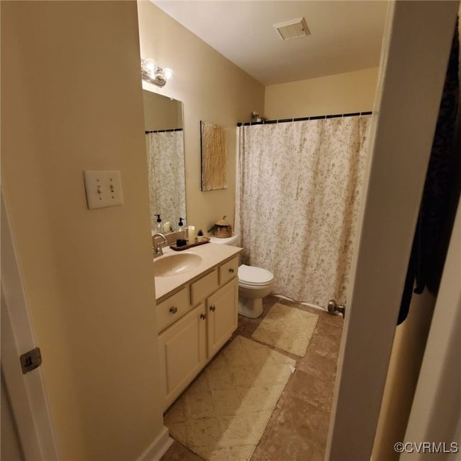 Full bathroom with visible vents, curtained shower, toilet, and vanity | Image 49
