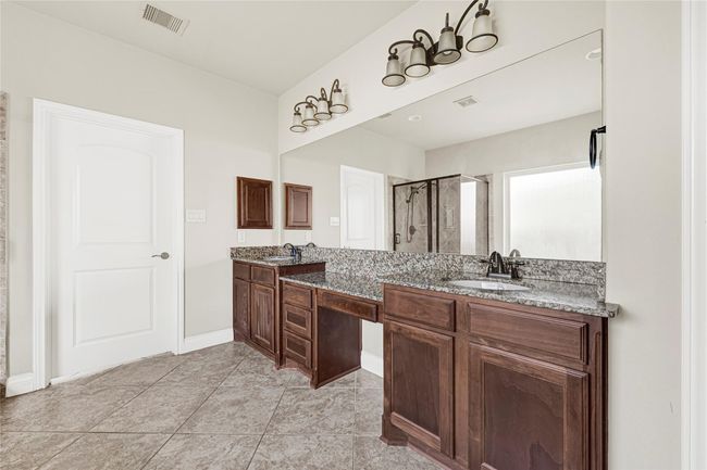 Dual vanities, wide counters, and access to two full-entry closets define the primary en suite bath, offering plenty of room to begin and end each day with comfort. | Image 25