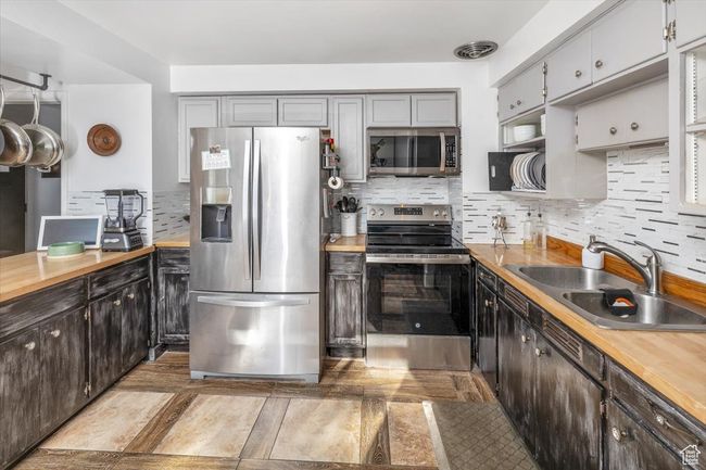 Kitchen featuring sink, backsplash, stainless steel appliances, and wood counters | Image 10