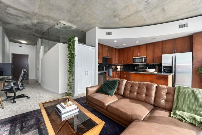 Living area with light carpet, a desk, and baseboards | Image 10