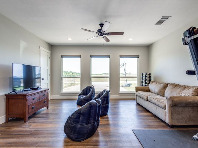 This second primary suite or second living area is perfect for a kids' living area or fourth "mini-primary" bedroom--double doors, ensuite bath, walk-in closets, recess lighting, fan, and beautiful views of the north acreage. | Image 24