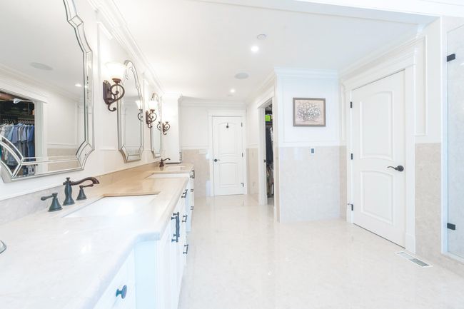 Bathroom featuring visible vents, crown molding, double vanity, a walk in closet, and a sink | Image 26