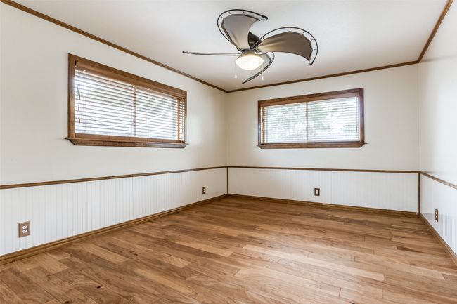 Unfurnished room with healthy amount of natural light, a ceiling fan, wainscoting, light wood-type flooring, and ornamental molding | Image 28