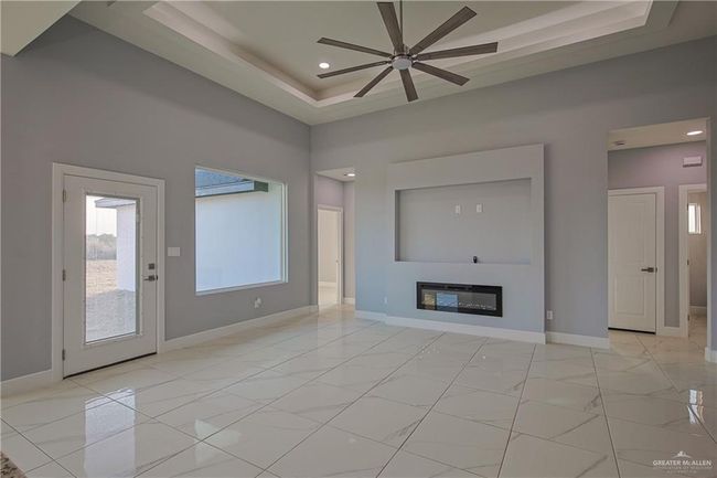 Unfurnished living room with a high ceiling, ceiling fan, and a raised ceiling | Image 5