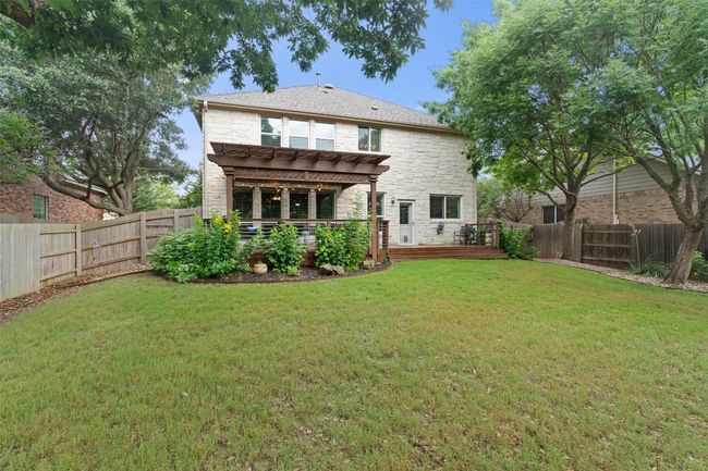 Rear view of property featuring stone siding, a pergola, and a deck | Image 30