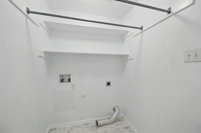 Laundry area with gas dryer hookup, electric dryer hookup, hookup for a washing machine, marble finish flooring, and baseboards | Image 6