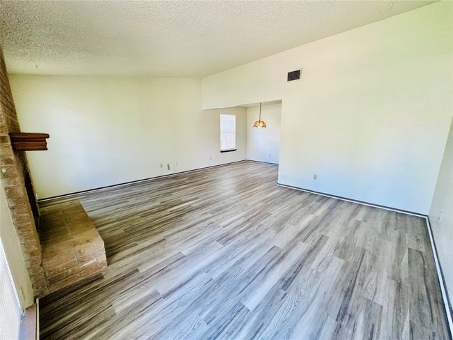 Unfurnished living room with a textured ceiling and wood finished floors | Image 6