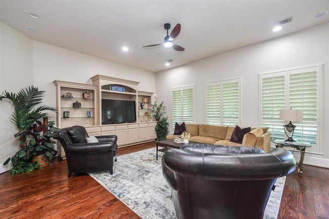 Spacious family room towards the rear of the home with lots of light and warmth. Timeless wood shutters and custom media center makes for the perfect entertainers delight combining comfort and style. | Image 22