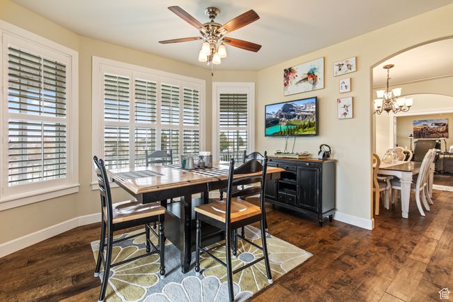 Dining room featuring ceiling fan with notable chandelier, plenty of natural light, and dark wood-type flooring | Image 36