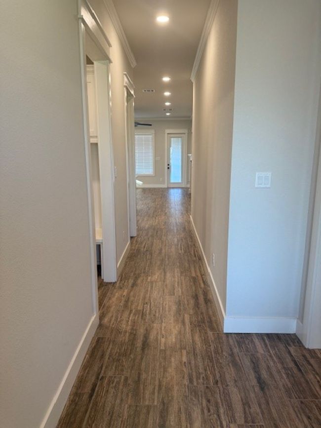 Corridor with dark wood finished floors, ornamental molding, and recessed lighting | Image 4