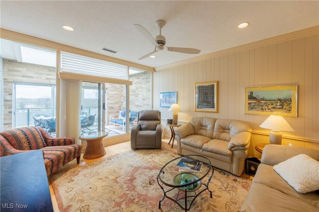 Den with crown molding, a ceiling fan, and visible vents | Image 24