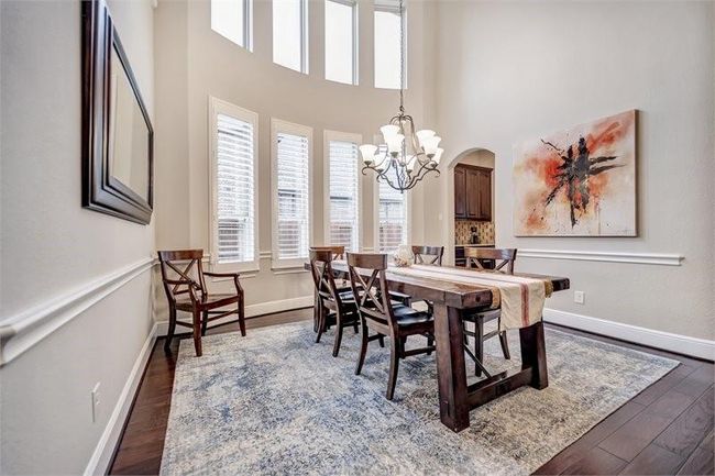 Elegant formal dining room features soaring ceilings and abundant natural light from large windows. | Image 11