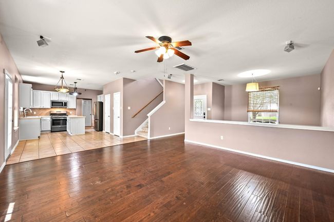 Unfurnished living room featuring a ceiling fan, stairs, and light wood-style floors | Image 10