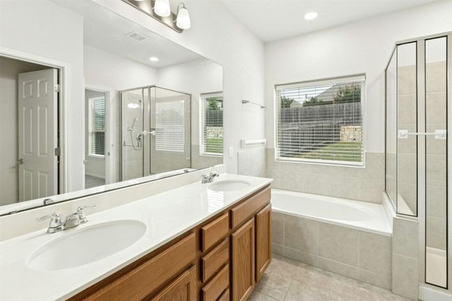 This primary ensuite bathroom is all about combining style with functionality, featuring dual vanities, walk-in shower and a separate garden tub. | Image 11