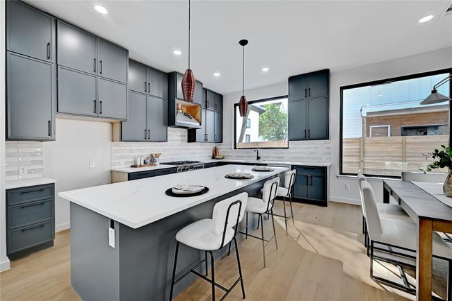 Kitchen featuring light wood-type flooring, a center island, gray cabinetry, and hanging light fixtures | Image 6