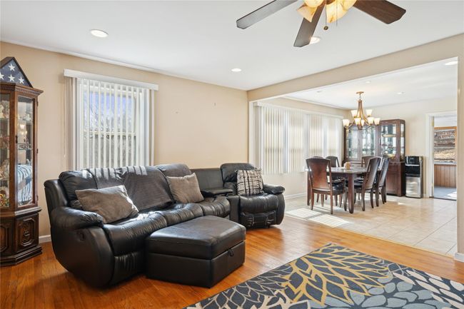 Living area featuring a wealth of natural light, ceiling fan with notable chandelier, and light wood finished floors | Image 14