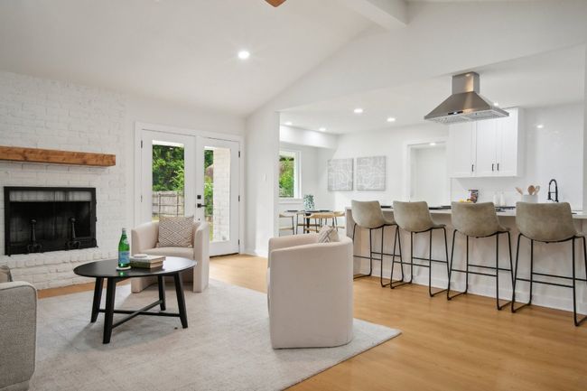 Living area featuring recessed lighting, light wood-style floors, a brick fireplace, and vaulted ceiling with beams | Image 7
