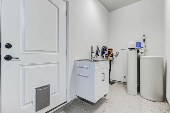 Inside the garage, you'll find durable epoxy flooring, a utility sink, and a water softener. The space also offers convenient storage for cleaning supplies and tools. | Image 23