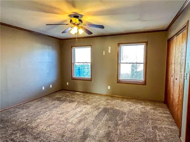 Carpeted spare room featuring crown molding, a ceiling fan, and a wealth of natural light | Image 11