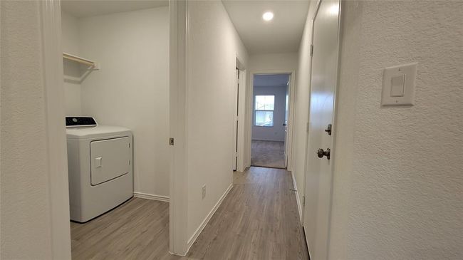 Laundry area with washer / dryer, wood finished floors, and a textured wall | Image 17