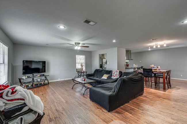Living room with ceiling fan, visible vents, baseboards, and wood finished floors | Image 12