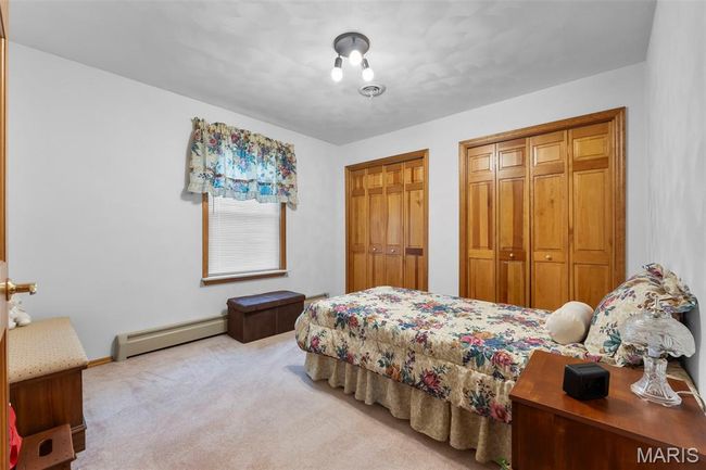 Carpeted bedroom with a baseboard heating unit and two closets | Image 77