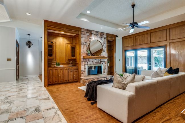 Living area featuring a stone fireplace, light wood-type flooring, a textured ceiling, recessed lighting, and ceiling fan | Image 6