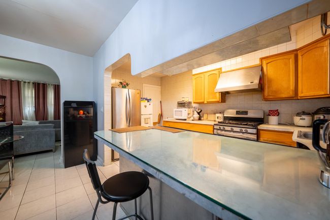 Kitchen with extractor fan, appliances with stainless steel finishes, a kitchen breakfast bar, arched walkways, and light tile patterned floors | Image 10