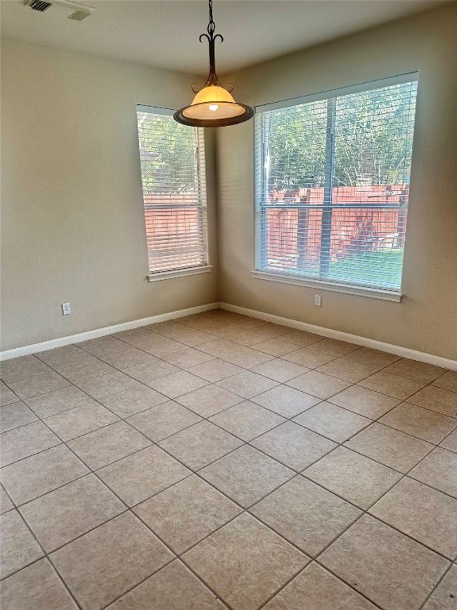 Empty room with healthy amount of natural light and light tile patterned floors | Image 7
