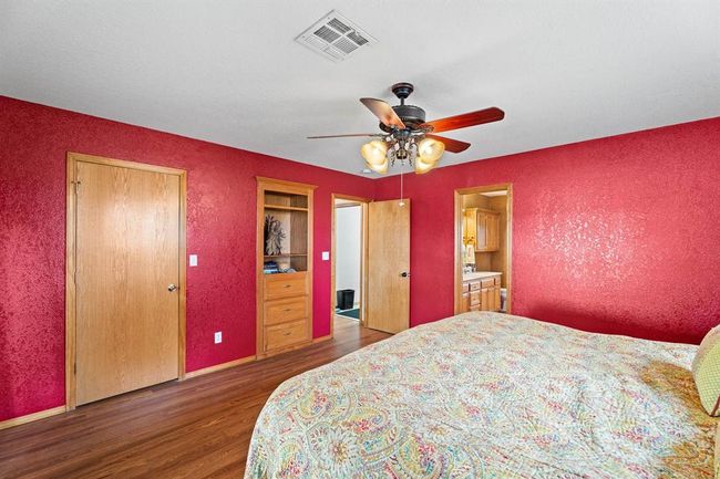 Bedroom with visible vents, wood finished floors, a textured wall, and a ceiling fan | Image 25