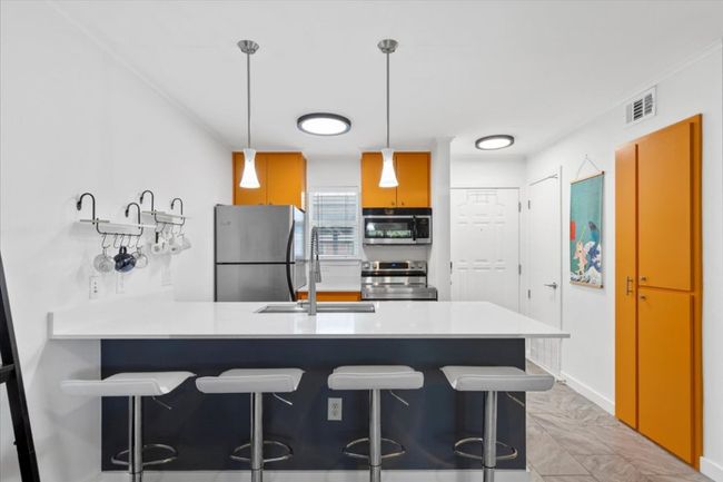 Kitchen featuring a peninsula, appliances with stainless steel finishes, light marble finish floors, and a kitchen breakfast bar | Image 5
