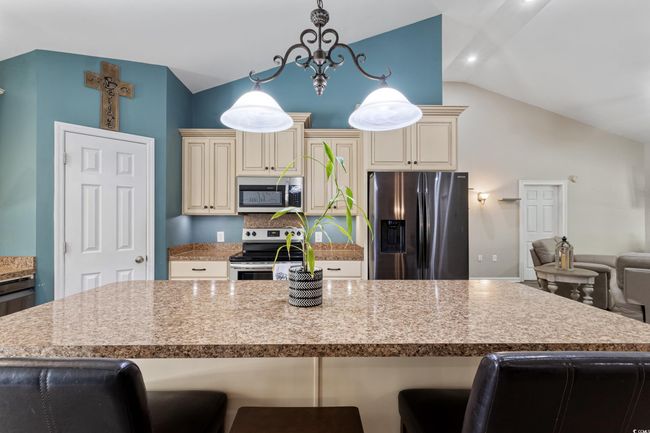 Kitchen with stainless steel appliances, cream cabinets, lofted ceiling, a breakfast bar area, and open floor plan | Image 13