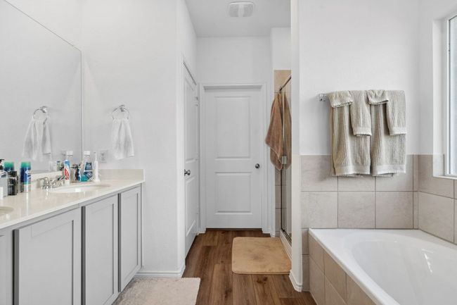 Full bath featuring a garden tub, wood finished floors, a sink, double vanity, and a stall shower | Image 19