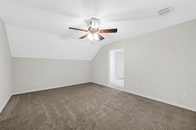 Additional living space featuring vaulted ceiling, visible vents, carpet floors, baseboards, and ceiling fan | Image 16