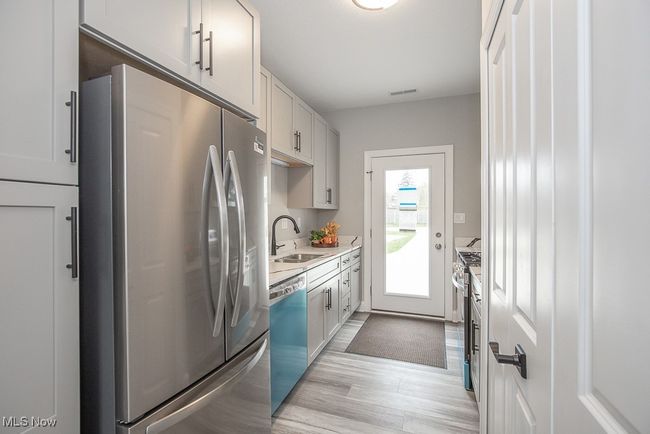 Kitchen with white cabinets, light hardwood / wood-style flooring, sink, and stainless steel appliances | Image 14